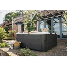 Eingebauter Whirlpool im Garten mit zwei Personen im Wasser, Korb und Decke