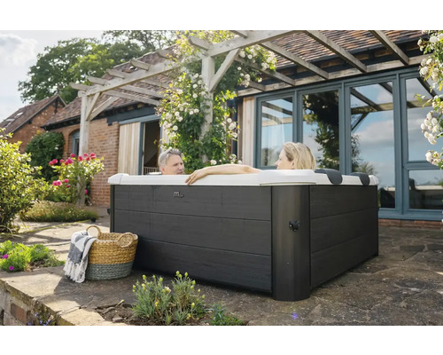 Eingebauter Whirlpool im Garten mit zwei Personen im Wasser, Korb und Decke