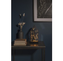 Dekoratives Arrangement mit LED-Leuchte, Vase, Büchern und gerahmtem Bild auf einem Tisch