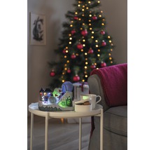 Dekorative Weihnachtsszene mit beleuchtetem Skihang, Tasse, Schale und Weihnachtsbaum im Hintergrund