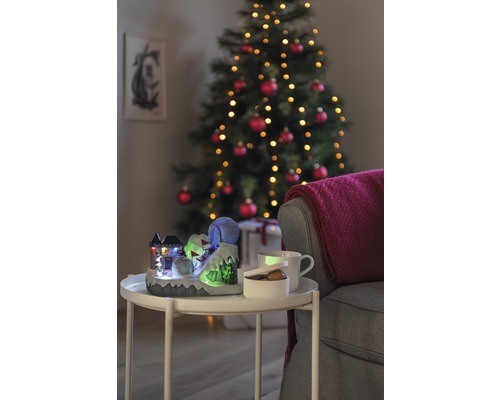 Dekorative Weihnachtsszene mit beleuchtetem Skihang, Tasse, Schale und Weihnachtsbaum im Hintergrund