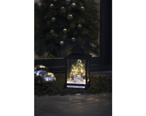 Dekorative Laterne mit Schneemann-Motiv und Weihnachtsbaum im Hintergrund