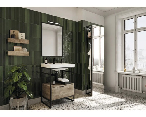 Badezimmer mit Waschbecken, Spiegel, Ablagen und grünen Fliesen.