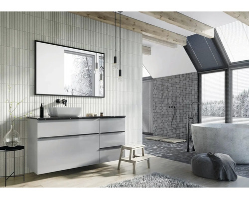 Helles Badezimmer mit Waschtisch, Spiegel, Badewanne und Mosaikfliesen an der Wand.