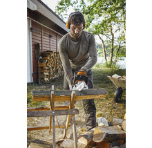 Mann sägt Holz mit einer Kettensäge auf einem Holzbock im Freien