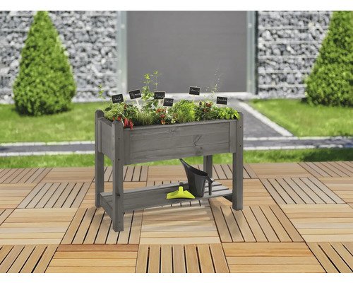 Hochbeet aus Holz mit Kräutern und Gartengeräten