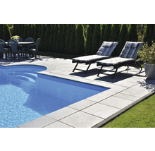 Schwimmbadbereich mit Becken, Steinplatten, Liegestühlen und Gartentisch mit Stühlen