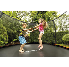 Zwei Kinder springen auf einem Gartentrampolin mit Sicherheitsnetz.