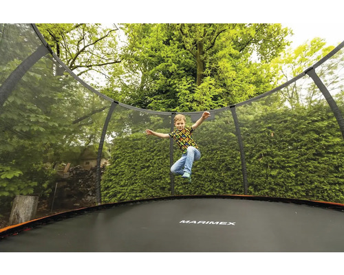 Kind springt auf einem Marimex Trampolin mit Sicherheitsnetz im Garten