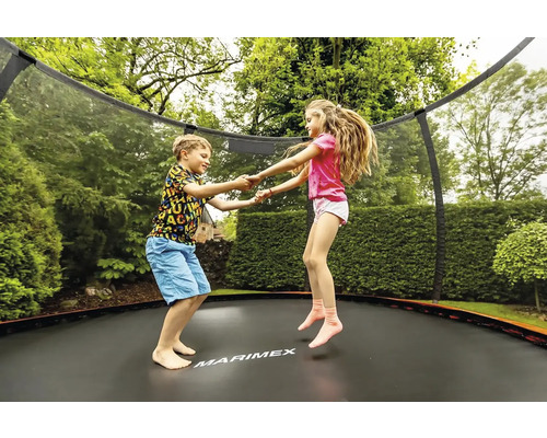 Zwei Kinder springen auf einem Gartentrampolin mit Sicherheitsnetz.