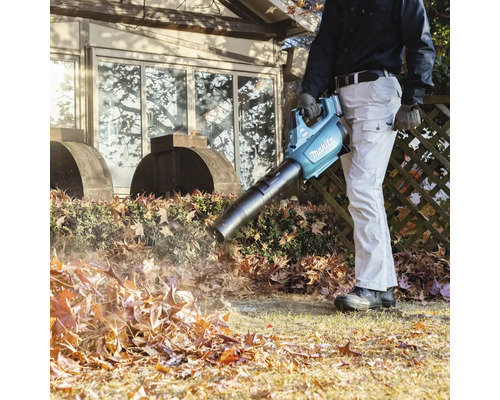 Ein Mann benutzt einen Akku-Laubbläser von Makita, um Blätter im Garten zu entfernen.