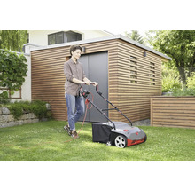 Frau benutzt einen elektrischen Rasenmäher auf einem Rasen