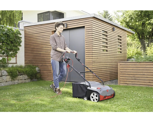 Frau benutzt einen elektrischen Rasenmäher auf einem Rasen