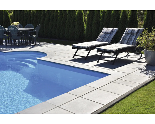 Szene mit Pool, Terrasse mit Steinplatten, Liegestühlen und Gartentisch mit Stühlen.