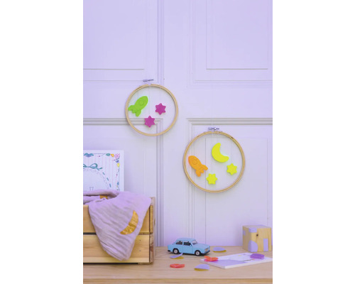 Dekorative Wandgestaltung mit Stickrahmen, Raketen und Sternen im Kinderzimmer.