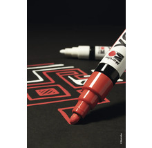 Roter Lackmarker zeichnet auf schwarzem Untergrund ein Muster, im Hintergrund weiterer Marker.