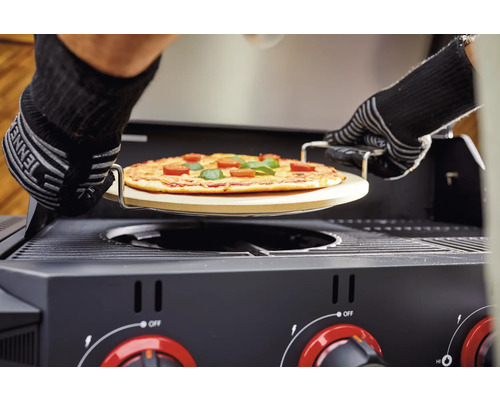 Pizza auf einem Pizzastein wird in einen Gasgrill geschoben