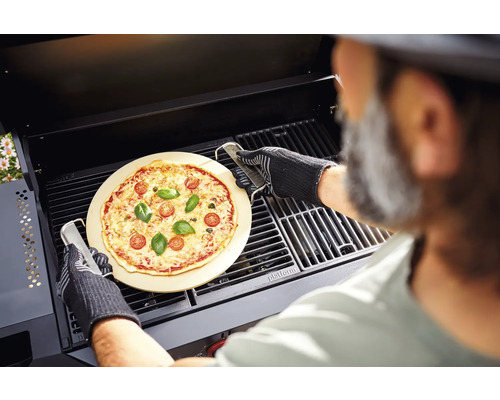 Eine Pizza auf einem Pizzastein wird mit einem Grill in einem Grill zubereitet.