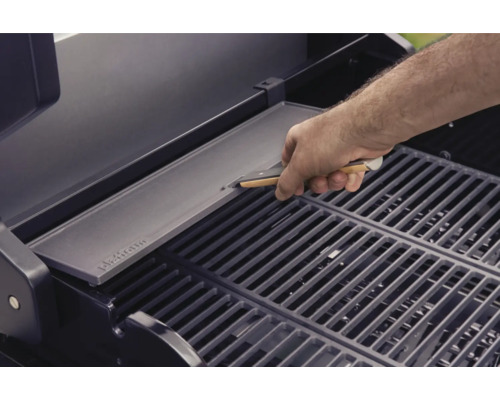 Ein Mann legt eine Grillplatte auf einen Grillrost.
