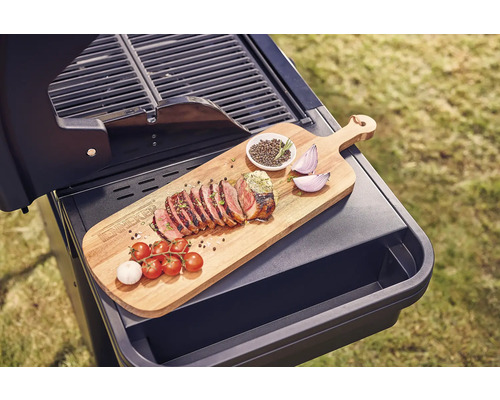 Grill mit Holzbrett, gegrilltem Fleisch, Tomaten, Knoblauch, Zwiebeln und Gewürzen