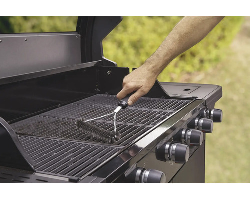 Eine Person reinigt einen Grillrost mit einer Grillbürste.