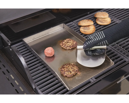 Burgerzubereitung auf Grillplatte mit Grillwender und Burgerbrötchen