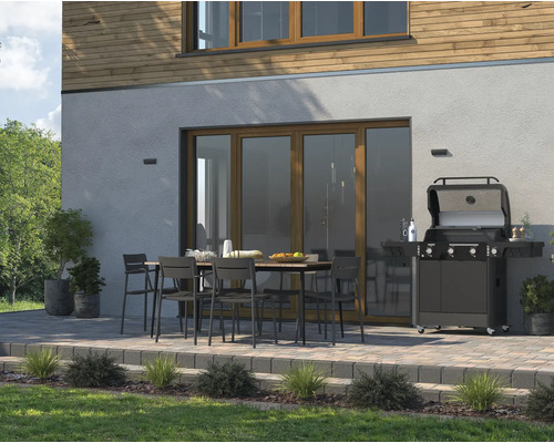 Terrasse mit Esstisch, Stühlen und Gasgrill vor einem Haus.