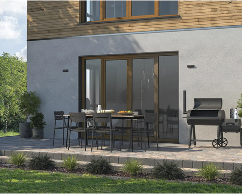 Außenbereich mit Terrasse, Gartentisch, Stühlen und Grill für entspannte Stunden im Freien.