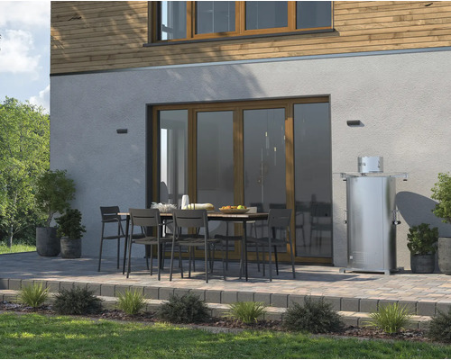 Terrasse mit Gartentisch, Stühlen und Heizstrahler vor einem Haus.