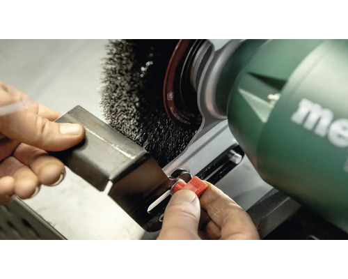 Metallstück wird mit einer Drahtbürste an einer Schleifmaschine bearbeitet