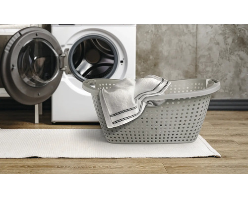 Wäschekorb mit Wäsche und Waschmaschine im Hintergrund