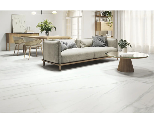 Wohnzimmer mit Sofa, Tisch und Bodenfliesen in Marmoroptik.