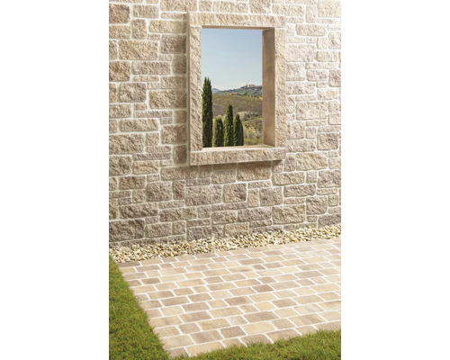 Eine gemauerte Wand mit Fenster und Pflastersteinen im Außenbereich.