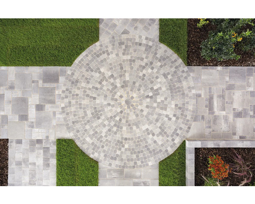 Gartengestaltung mit Pflastersteinen in Kreisform, umgeben von Rasenflächen und Blumenbeeten.
