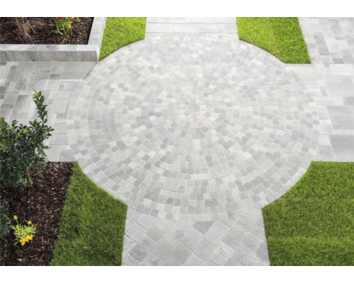 Kreisförmige Pflasterfläche im Garten mit Rasenflächen.
