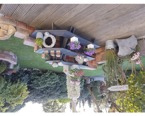 Dekorativer Gartenbereich mit Regal, Pflanzen und Gartenschild