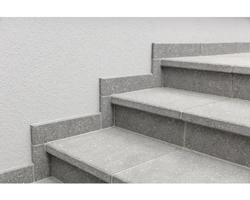Treppe mit grauen Fliesen und Sockelleisten an einer Wand