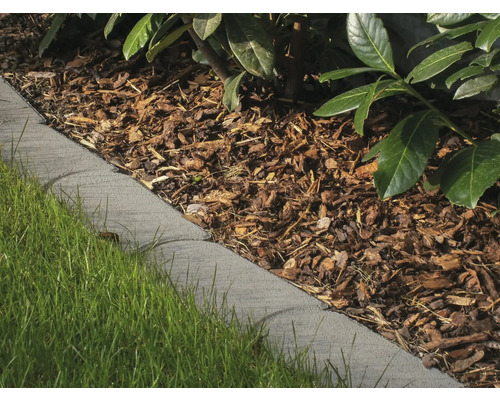 Nahaufnahme einer grauen Rasenkante, die einen Gartenweg von einem Rasen trennt