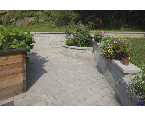 Gestalteter Gartenbereich mit Pflastersteinen und Mauerelementen
