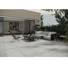Terrasse mit grauen Steinplatten, Sitzgruppe und Blick in ein Wohnzimmer