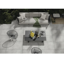 Gartenmöbel-Set auf einer Steinterrasse mit Sofa, Tisch und Stühlen aus Metall.