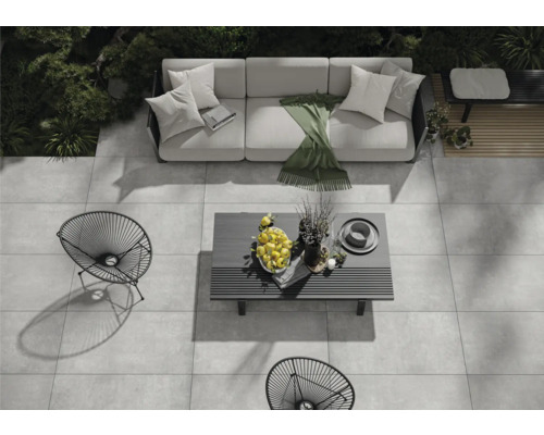 Gartenmöbel-Set auf einer Steinterrasse mit Sofa, Tisch und Stühlen aus Metall.