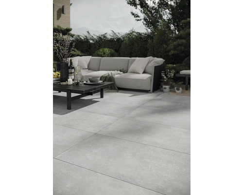 Terrasse mit großformatigen Steinzeugfliesen, Sofagarnitur und Tisch im Außenbereich.