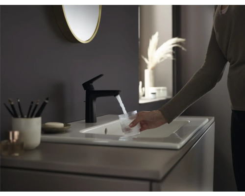 Badezimmer Szene mit Waschbecken, Armatur, Spiegel und einer Person, die ein Glas Wasser füllt