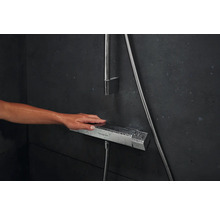 Nahaufnahme einer Hand, die einen Duschthermostat der Marke Hansgrohe bedient.