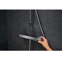 Aufnahme einer Hand, die einen Duschthermostat von Hansgrohe in einem Badezimmer bedient
