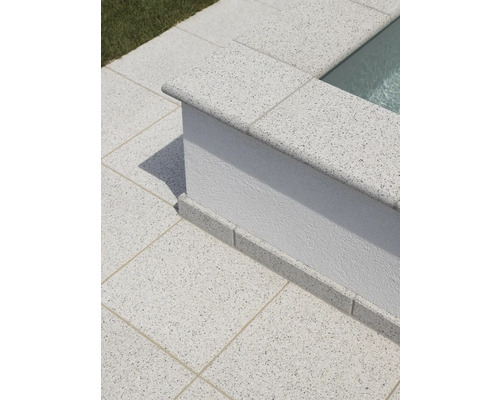 Terrassenplatten aus Stein umranden einen Poolbereich.