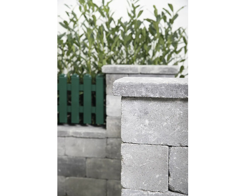 Mauer aus Betonsteinen mit Zaun im Garten