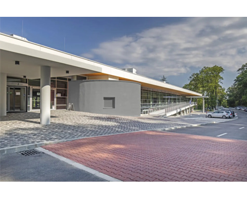 Außenansicht eines modernen Gebäudes mit Pflastersteinen und Parkplatz