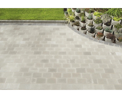 Gepflasterter Gartenweg mit Rasenfläche und bepflanztem Hang